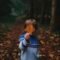 boy holding brown leaf covering his face